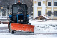 ein-traktor-reinigt-im-winter-nach-einem-schneefall-schnee-in-der-stadt-reinigung-der-strassen-der-stadt-vom-schnee-traktorfahrer-bei-der-arbeit-auf-dem-stadtplatz-waehrend-eines-schneesturms